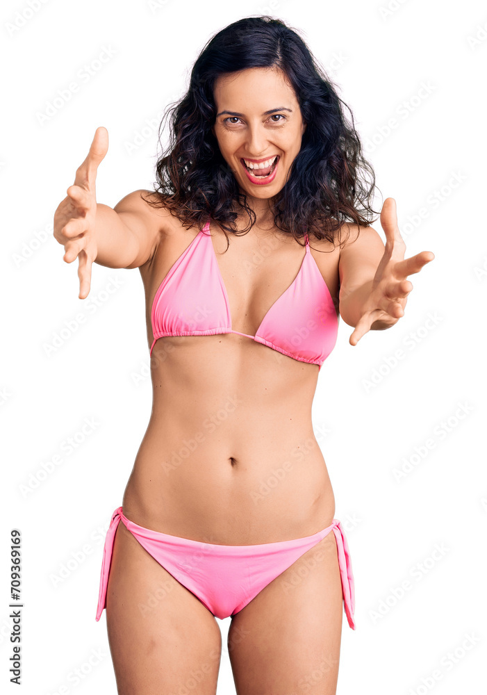Young beautiful hispanic woman wearing bikini looking at the camera smiling with open arms for hug. cheerful expression embracing happiness. Young beautiful hispanic woman wearing bikini looking at the camera smiling with open arms for hug. cheerful expression embracing happiness.
