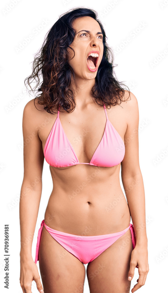 Obraz premium Young beautiful hispanic woman wearing bikini angry and mad screaming frustrated and furious, shouting with anger. rage and aggressive concept.
