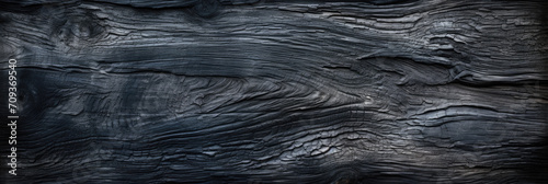Burnt wood texture background, wide banner of scorched black tree. Abstract pattern of dark burned charred timber. Concept of charcoal, coal, grill, embers, tree, firewood, fire