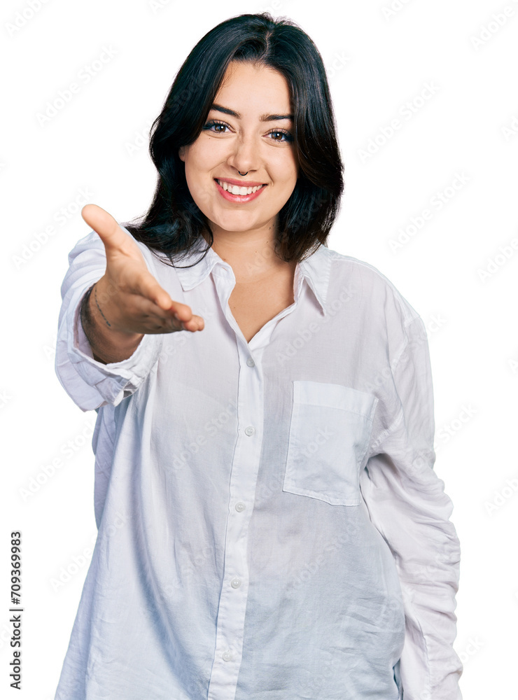 Beautiful hispanic woman wearing casual white shirt smiling friendly offering handshake as greeting and welcoming. successful business. Beautiful hispanic woman wearing casual white shirt smiling friendly offering handshake as greeting and welcoming. successful business.