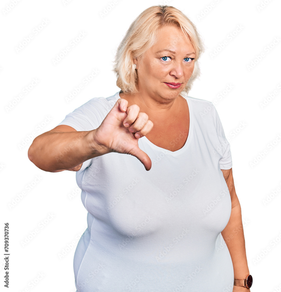 Middle age blonde woman wearing casual white t shirt looking unhappy and angry showing rejection and negative with thumbs down gesture. bad expression. Middle age blonde woman wearing casual white t shirt looking unhappy and angry showing rejection and negative with thumbs down gesture. bad expression.