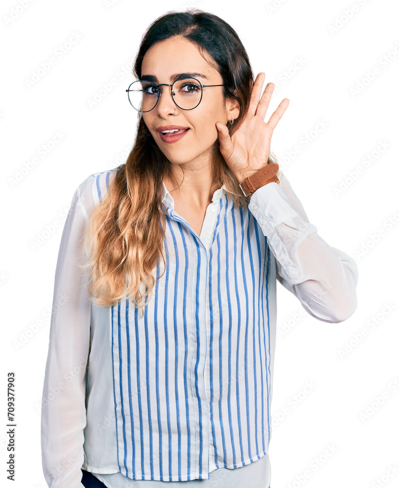 Beautiful hispanic woman wearing casual striped shirt smiling with hand over ear listening an hearing to rumor or gossip. deafness concept. Beautiful hispanic woman wearing casual striped shirt smiling with hand over ear listening an hearing to rumor or gossip. deafness concept.