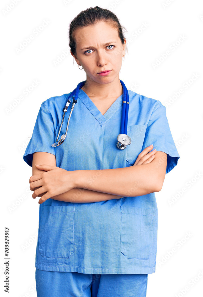 Young beautiful blonde woman wearing doctor uniform and stethoscope skeptic and nervous, disapproving expression on face with crossed arms. negative person. Young beautiful blonde woman wearing doctor uniform and stethoscope skeptic and nervous, disapproving expression on face with crossed arms. negative person.