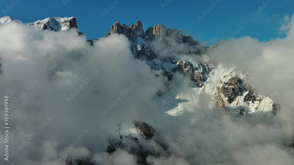Flying through beautiful white fluffy clouds between high rocky mountains. Dolomites Alps mountains, Italy, 4k