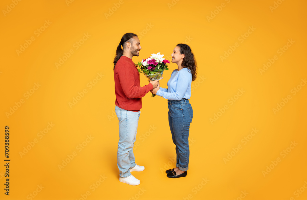 A smiling man gives a lush bouquet to a woman A smiling man gives a lush bouquet to a woman