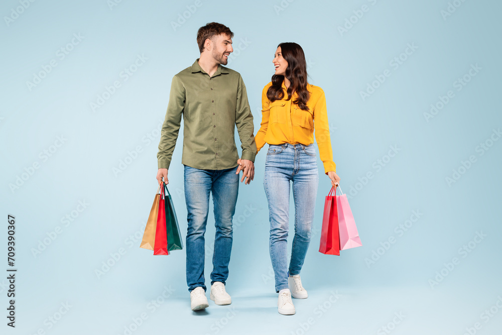 Smiling couple holding hands and shopping bags, content and casual
