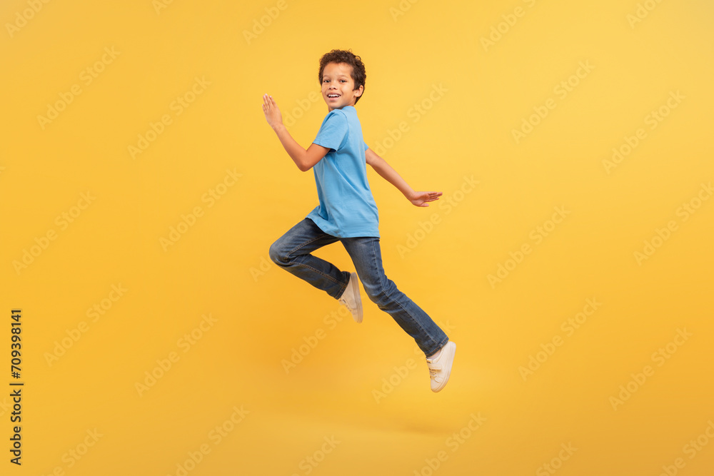 Black boy in mid-run on bright yellow background