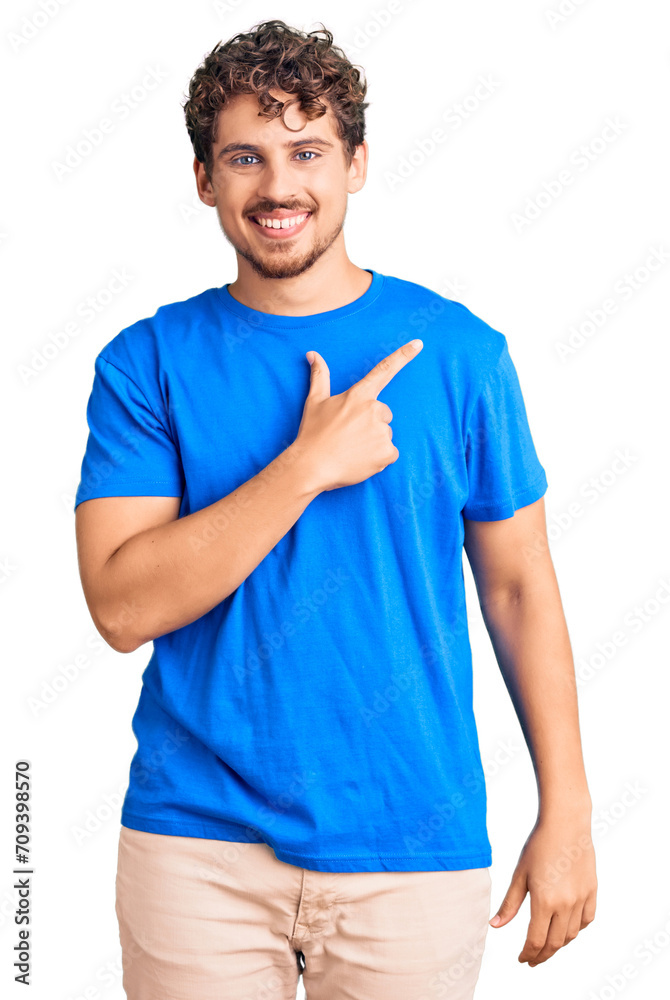 Young handsome man with curly hair wearing casual clothes cheerful with a smile on face pointing with hand and finger up to the side with happy and natural expression Young handsome man with curly hair wearing casual clothes cheerful with a smile on face pointing with hand and finger up to the side with happy and natural expression