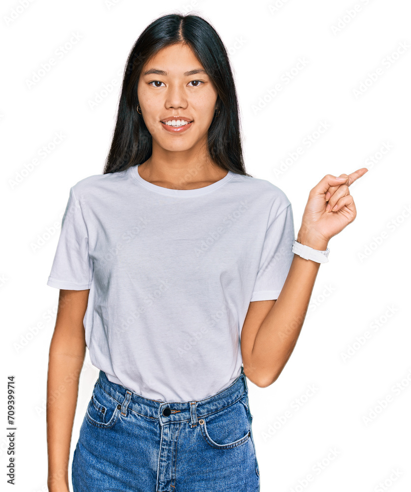 Beautiful young asian woman wearing casual white t shirt with a big smile on face, pointing with hand finger to the side looking at the camera. Beautiful young asian woman wearing casual white t shirt with a big smile on face, pointing with hand finger to the side looking at the camera.