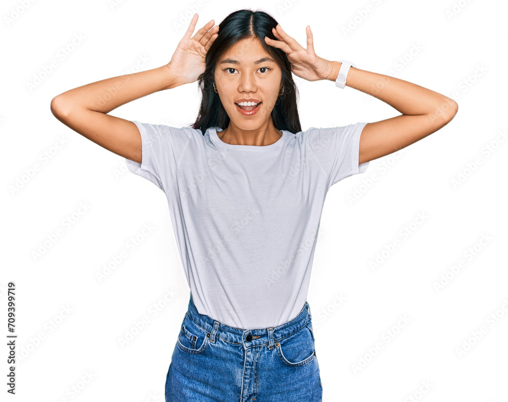 Beautiful young asian woman wearing casual white t shirt smiling cheerful playing peek a boo with hands showing face. surprised and exited Beautiful young asian woman wearing casual white t shirt smiling cheerful playing peek a boo with hands showing face. surprised and exited