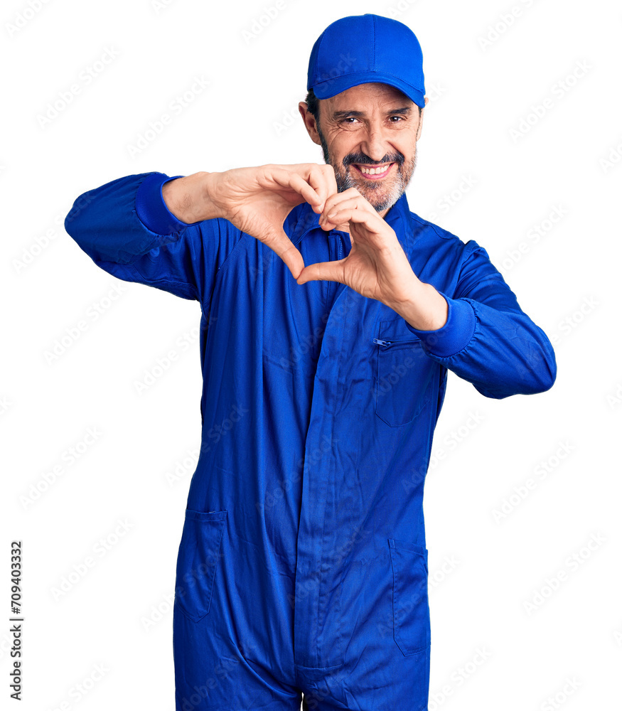 Middle age handsome man wearing mechanic uniform smiling in love doing heart symbol shape with hands. romantic concept.
