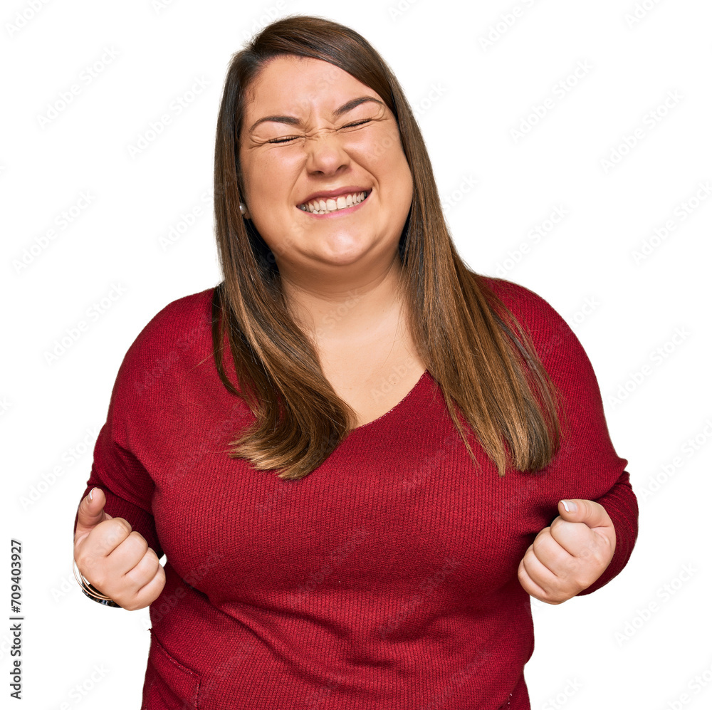 Beautiful brunette plus size woman wearing casual clothes very happy and excited doing winner gesture with arms raised, smiling and screaming for success. celebration concept.