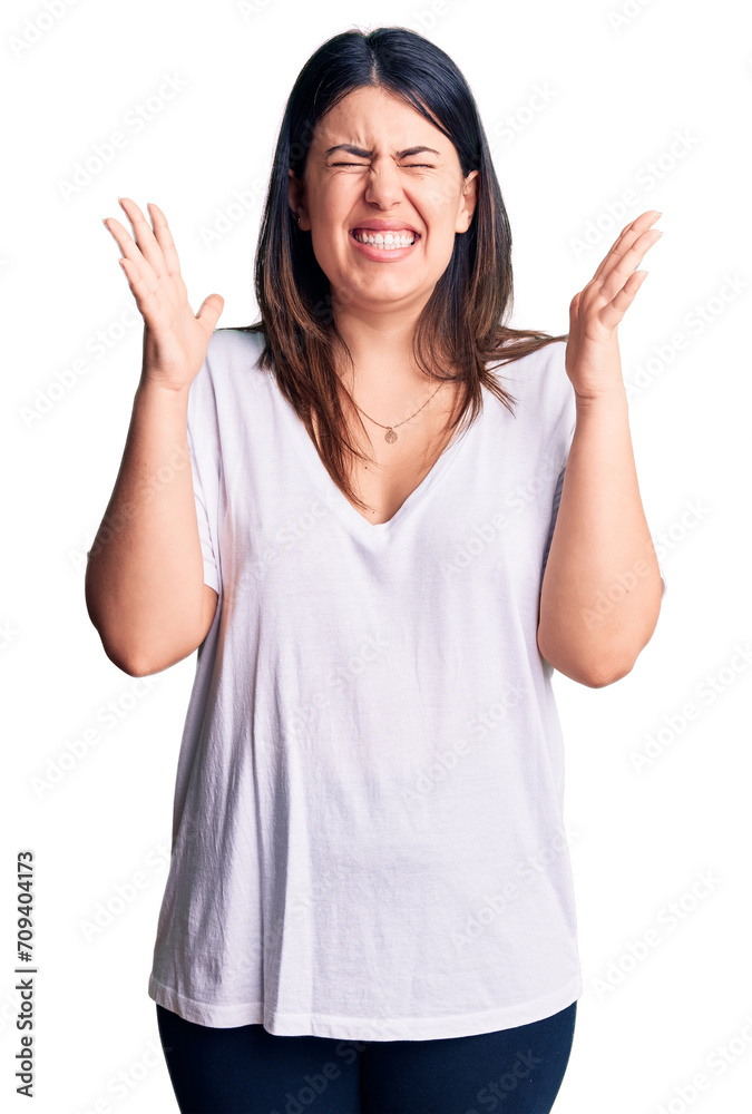 Young beautiful brunette woman wearing casual t-shirt celebrating mad and crazy for success with arms raised and closed eyes screaming excited. winner concept Young beautiful brunette woman wearing casual t-shirt celebrating mad and crazy for success with arms raised and closed eyes screaming excited. winner concept