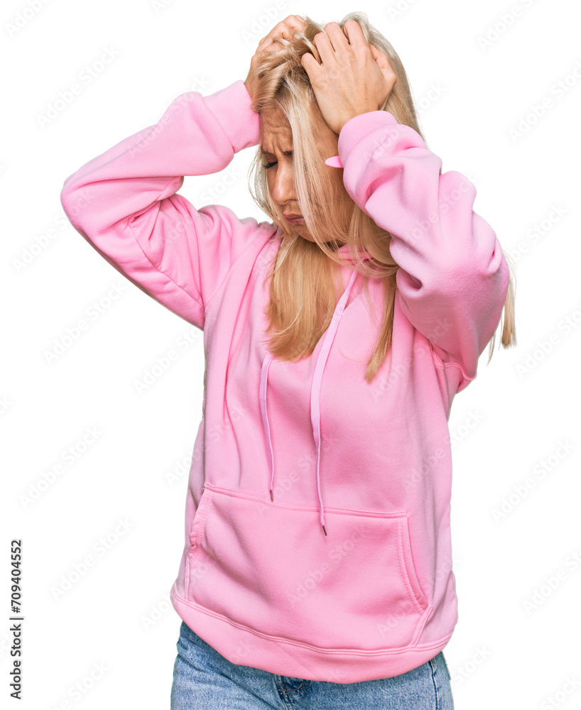 Young blonde woman wearing casual sweatshirt suffering from headache desperate and stressed because pain and migraine. hands on head. Young blonde woman wearing casual sweatshirt suffering from headache desperate and stressed because pain and migraine. hands on head.