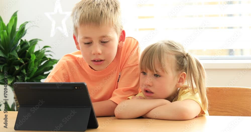 Cute brother and sister joyfully use the tablet together. Digital technologies. Cute brother and sister joyfully use the tablet together. Digital technologies.