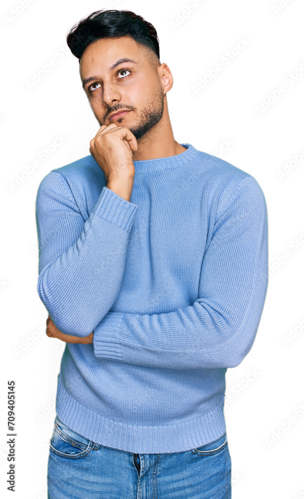 Young arab man wearing casual clothes serious face thinking about question with hand on chin, thoughtful about confusing idea Young arab man wearing casual clothes serious face thinking about question with hand on chin, thoughtful about confusing idea