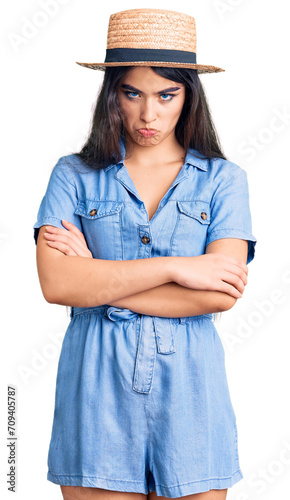 Brunette teenager girl wearing summer hat skeptic and nervous, disapproving expression on face with crossed arms. negative person.