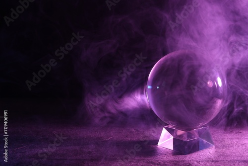 Crystal ball on table and smoke against dark background, space for text. Predictions of future