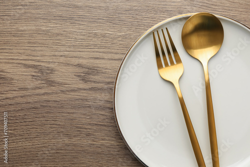 Plate  fork and spoon on wooden table  top view. Space for text