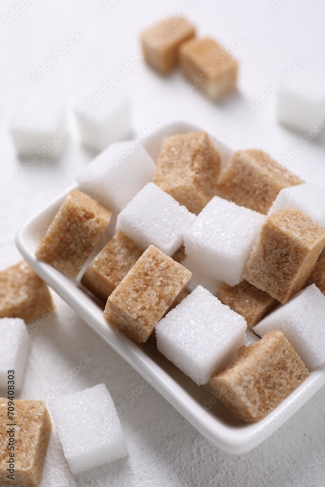 Different sugar cubes in bowl on white table, closeup Different sugar cubes in bowl on white table, closeup