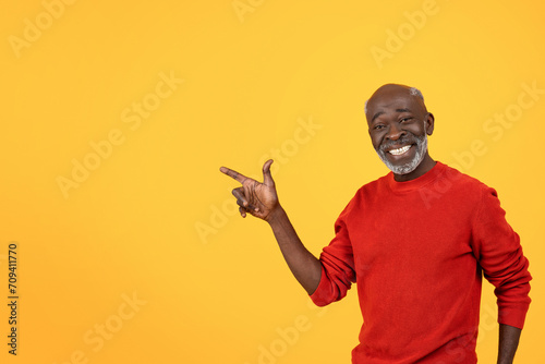 Happy senior Black man with a white beard, pointing to the side with a big smile photo