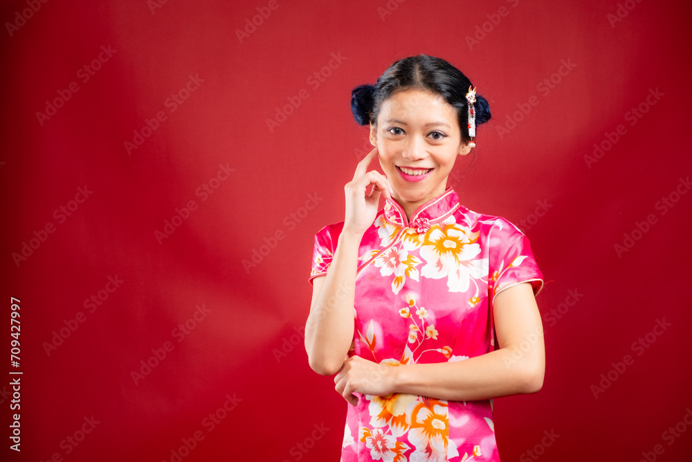 Portrait of an attractive Asian Chinese female wearing cheongsam or qipao on red background for Chinese New Year concept Portrait of an attractive Asian Chinese female wearing cheongsam or qipao on red background for Chinese New Year concept