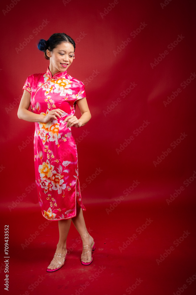 Portrait of an attractive Asian Chinese female wearing cheongsam or qipao on red background for Chinese New Year concept Portrait of an attractive Asian Chinese female wearing cheongsam or qipao on red background for Chinese New Year concept
