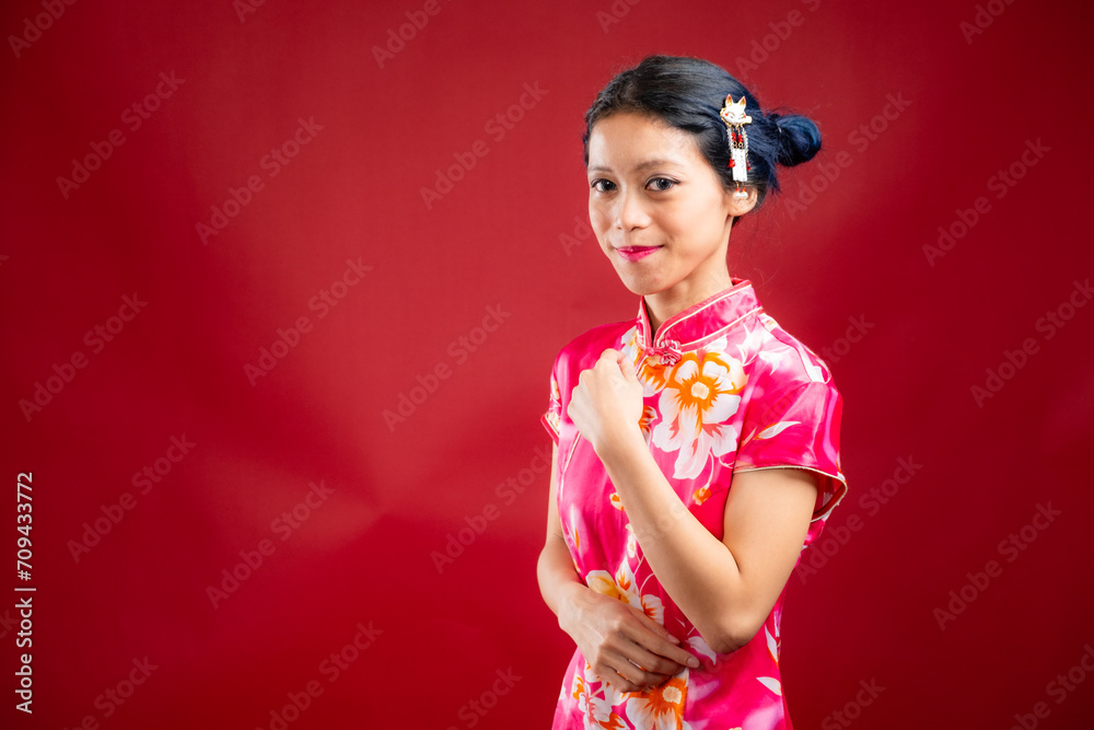 Portrait of an attractive Asian Chinese female wearing cheongsam or qipao on red background for Chinese New Year concept Portrait of an attractive Asian Chinese female wearing cheongsam or qipao on red background for Chinese New Year concept