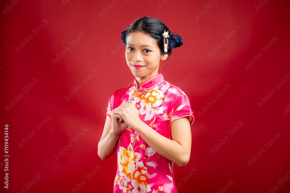 Portrait of an attractive Asian Chinese female wearing cheongsam or qipao on red background for Chinese New Year concept Portrait of an attractive Asian Chinese female wearing cheongsam or qipao on red background for Chinese New Year concept