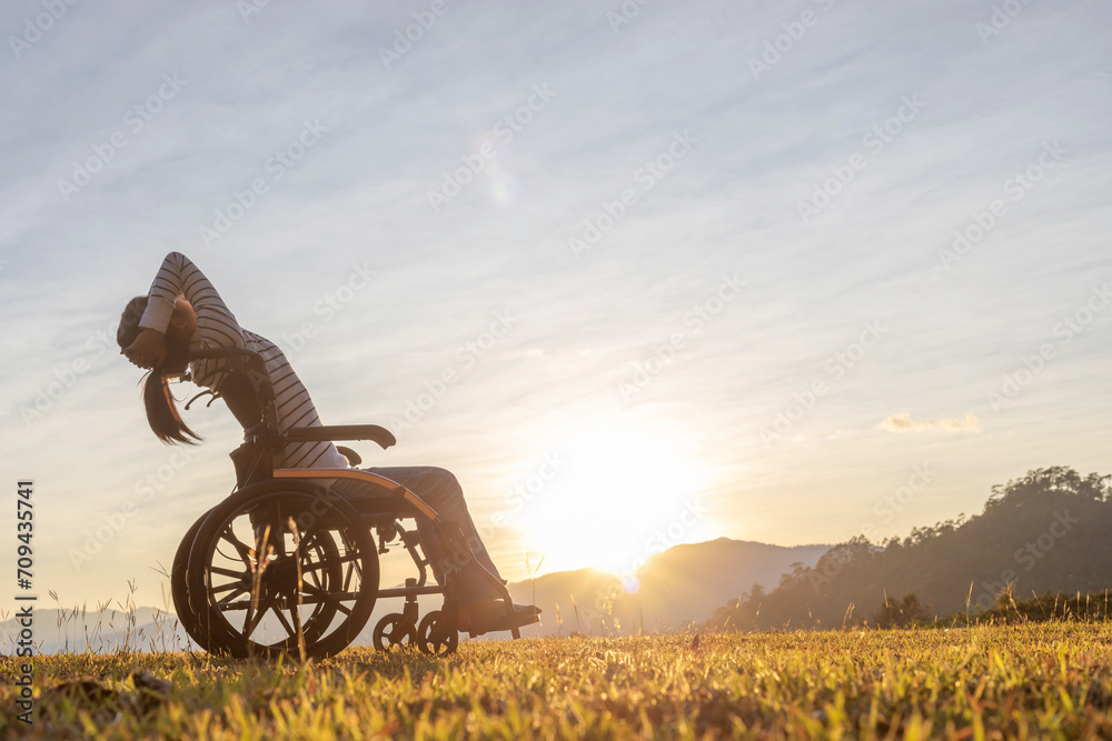 Silhouette Girl in wheelchair looking sunset mountain background. - obrazy, fototapety, plakaty 
