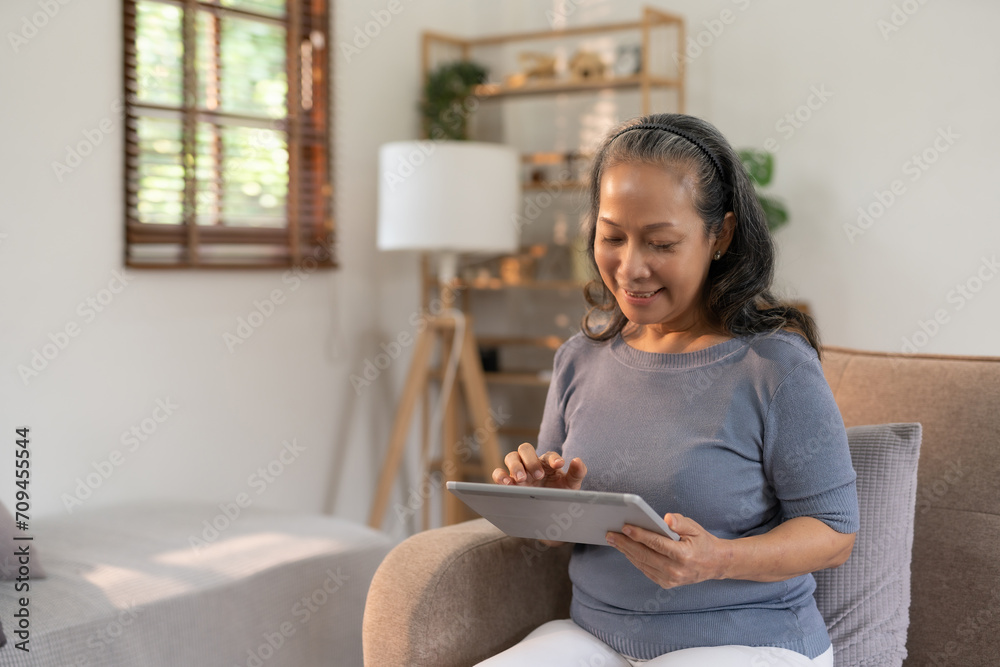 Senior asian woman sitting on sofa using tablet, working, chatting, social media internet at home. Senior asian woman sitting on sofa using tablet, working, chatting, social media internet at home.