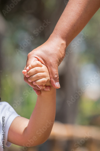 Little kid holding family member mother hand as a together family © natrocfort