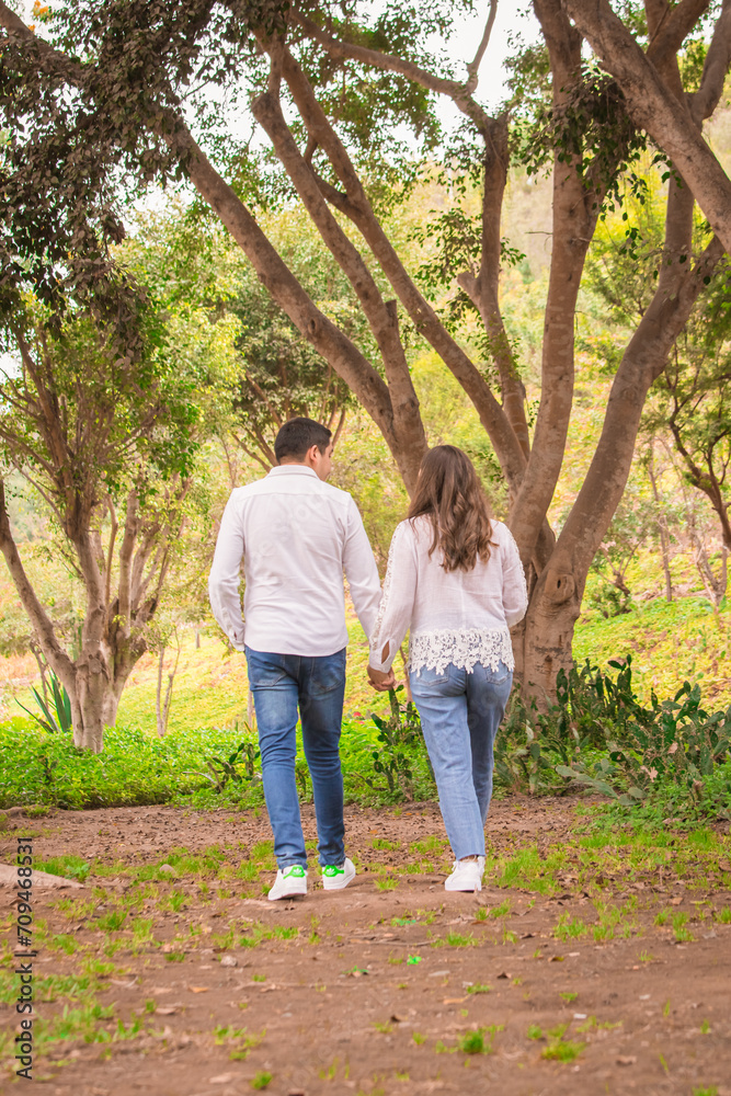 Family members holding hands and walking backwards in a park together family Family members holding hands and walking backwards in a park together family