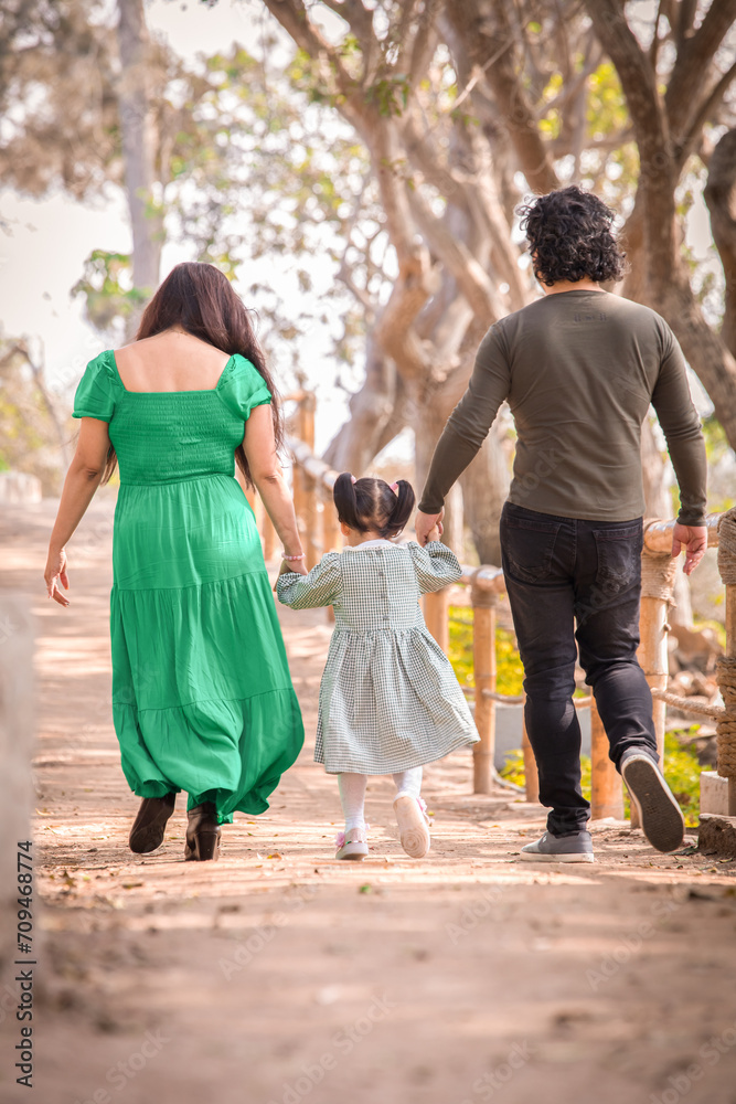 Fototapeta premium Family members holding hands and walking backwards in a park together family