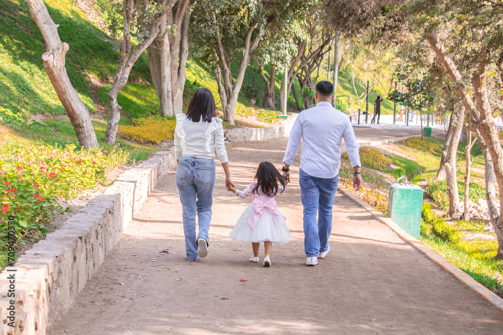 Family members holding hands and walking backwards in a park together family Family members holding hands and walking backwards in a park together family