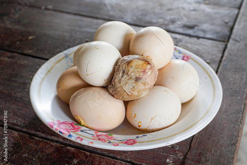 Pile of Steamed egg spoiled while being incubated on white plate place on wooden table. Eggs that do not hatch are hard-boiled. weird food.