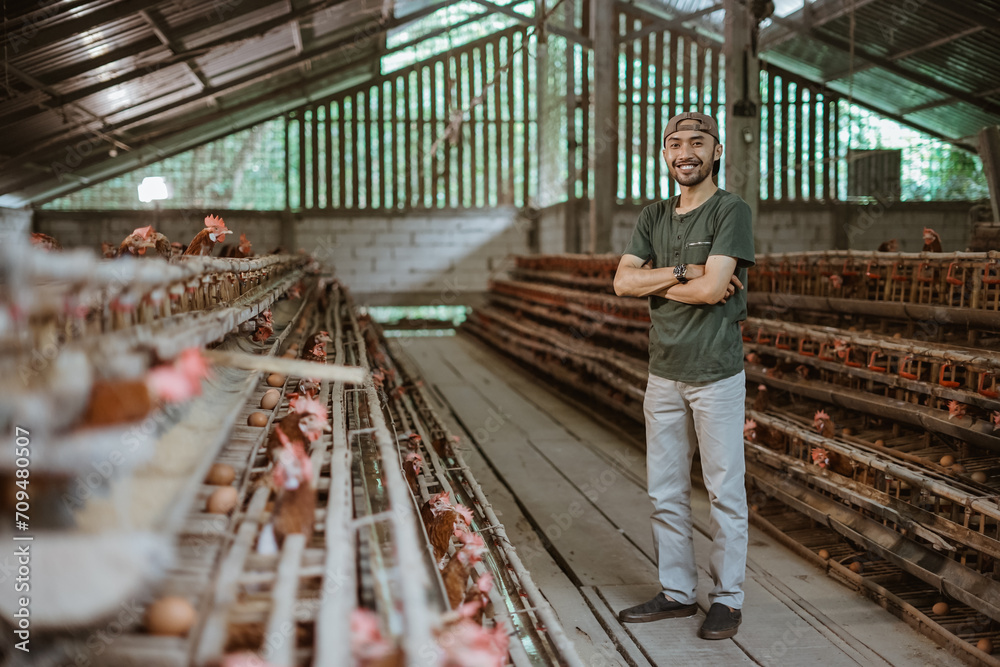 Asian man farm owner standing with crossed hands at chicken farm
