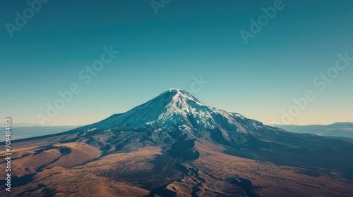 Aerial view of a lone, snow-capped mountain peak, at sunset