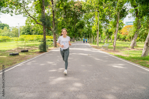 A happy little girl runs along a path in a park