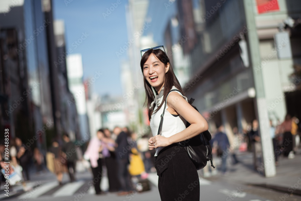 Dynamic city life, Positive and happy Japanese lady 30s, confidently navigating the urban streets of Tokyo.