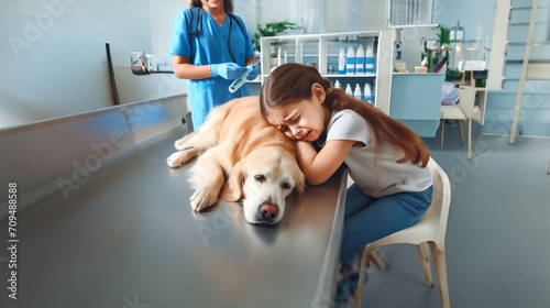 Petite fille chez le vétérinaire qui pleure la mort de son chien un Golden retriever , qui vient d'être euthanasié sur la table de consultation. Le vétérinaire est derrière avec la seringue photo