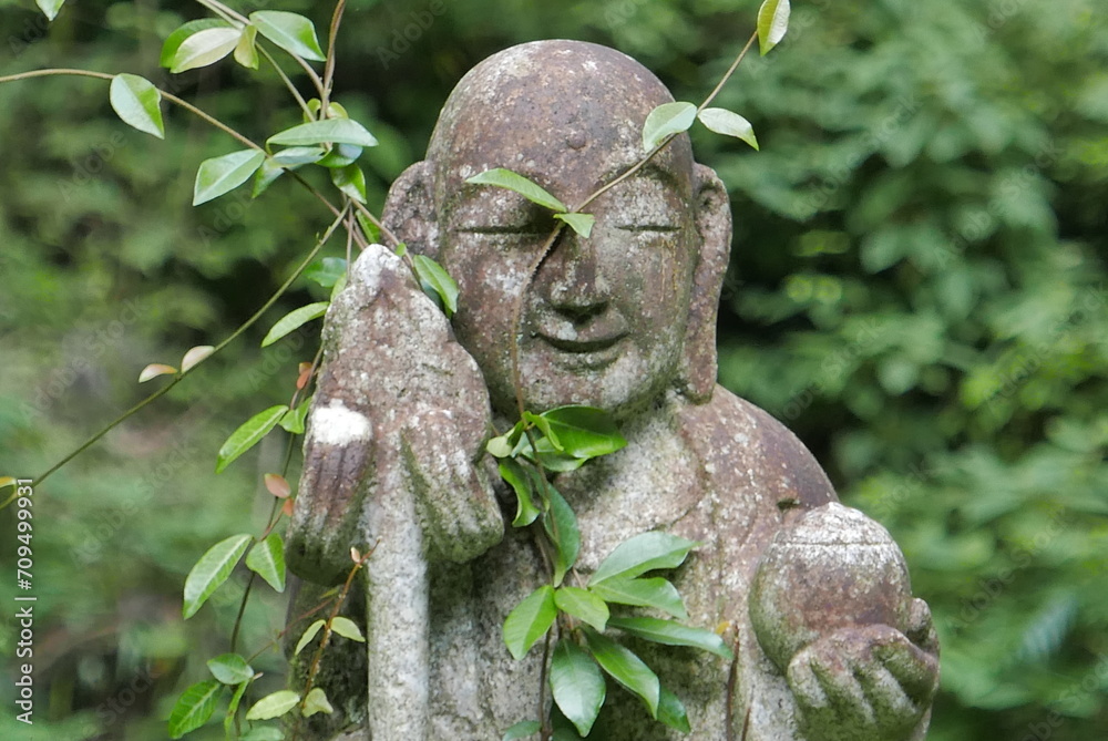 Obraz premium 森の中にあるお地蔵様の顔のアップ 地蔵 緑 木 山の中