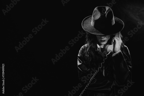 Dark noir portrait of a female detective holding a retro telephone receiver. Private detective, spy, investigation concept. black and white snapshot