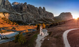 South Tyrol, Italy - Aerial panoramic view of the Chapel of San Maurizio (Cappella Di San Maurizio) at the Passo Gardena Pass in the Italian Dolomites at autumn with clear blue sky and setting sun