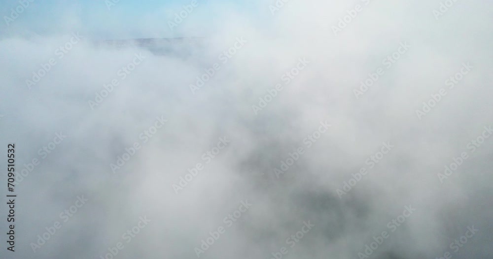 Aerial view through a thick, white fog cloud above the sea on a sunny morning Aerial view through a thick, white fog cloud above the sea on a sunny morning