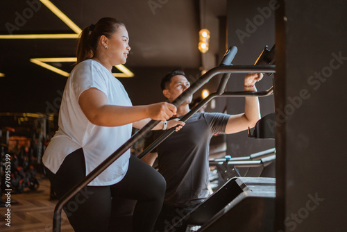 plus size woman doing cardio work out for wight loss program with her personal trainer photo