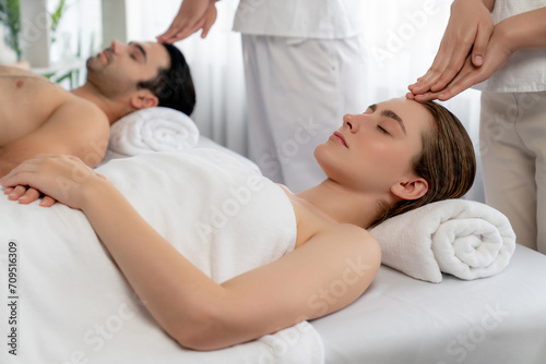 Caucasian couple enjoying relaxing anti-stress head massage and pampering facial beauty skin recreation leisure in dayspa modern light ambient at luxury resort or hotel spa salon. Quiescent photo