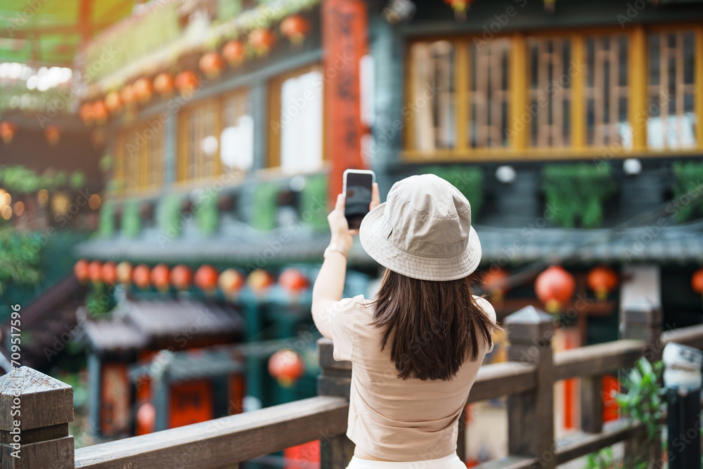 Fototapeta premium woman traveler visiting in Taiwan, Tourist taking photo and sightseeing in Jiufen Old Street village with Tea House background. landmark and popular attractions near Taipei city. Travel concept