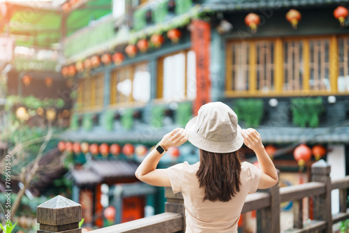 woman traveler visiting in Taiwan, Tourist with hat sightseeing in Jiufen Old Street village with Tea House background. landmark and popular attractions near Taipei city . Travel and Vacation concept