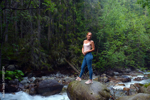 Young woman near Kezmarska Biela voda, the creek from the Tatra mountain in the valley